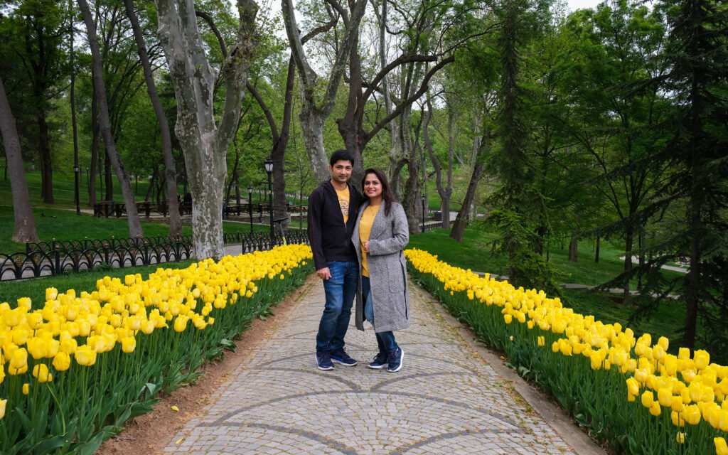 "A couple standing on a garden road lined by yellow tulip."