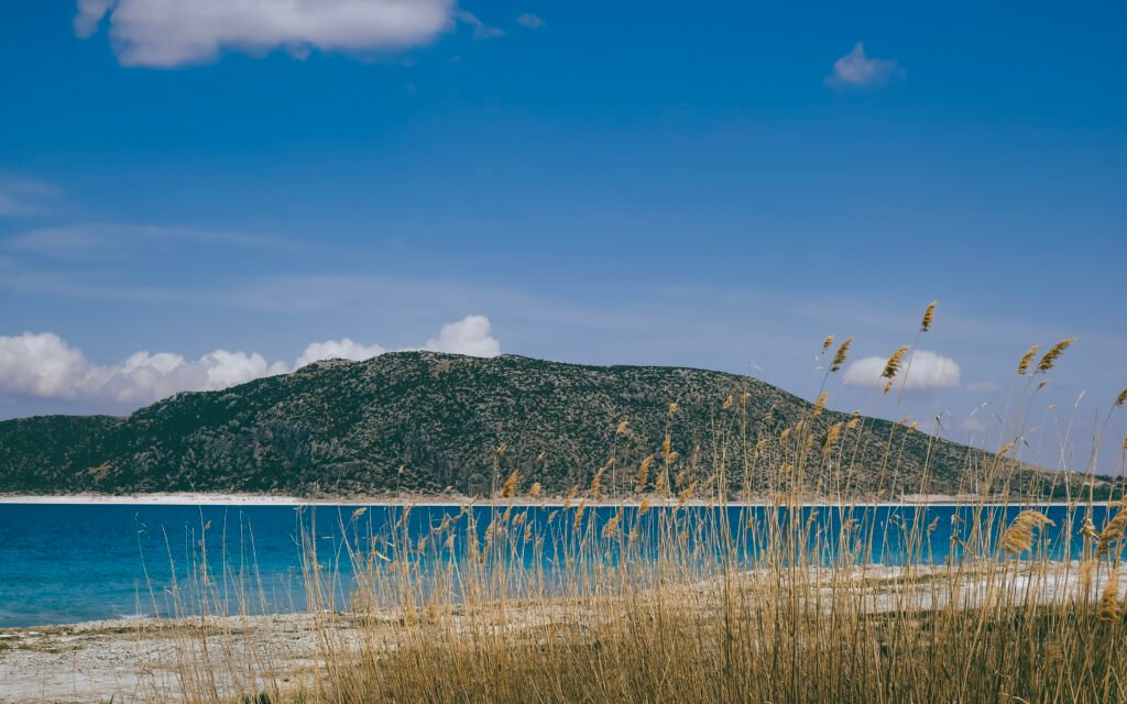 An image of a blue lake with a hill on the bank.